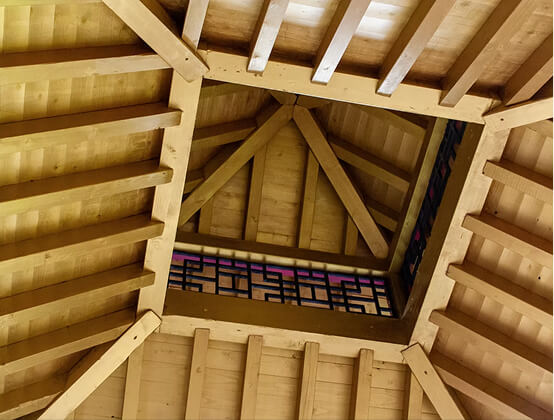 Innenansicht einer Holz-Dachkonstruktion mit geometrischen Mustern und Balken.