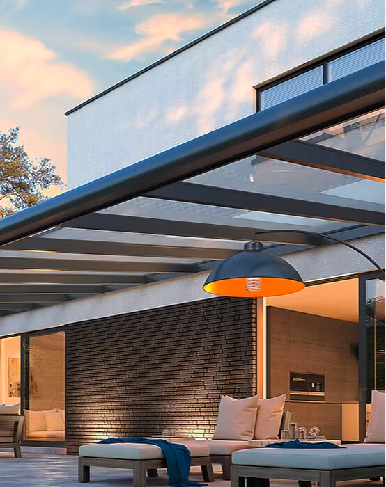 Moderne Terrasse mit Glasdach und Sitzbereich bei Abenddämmerung.