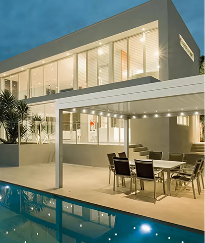 Modernes zweistöckiges Haus mit beleuchtetem Außenbereich und Swimmingpool in der Abenddämmerung.
