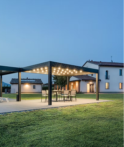 Beleuchtete Pergola auf Terrasse neben Haus bei Abenddämmerung.
