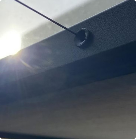 Kabeldurchführung an einem Fensterrahmen mit Sonnenlicht im Hintergrund.