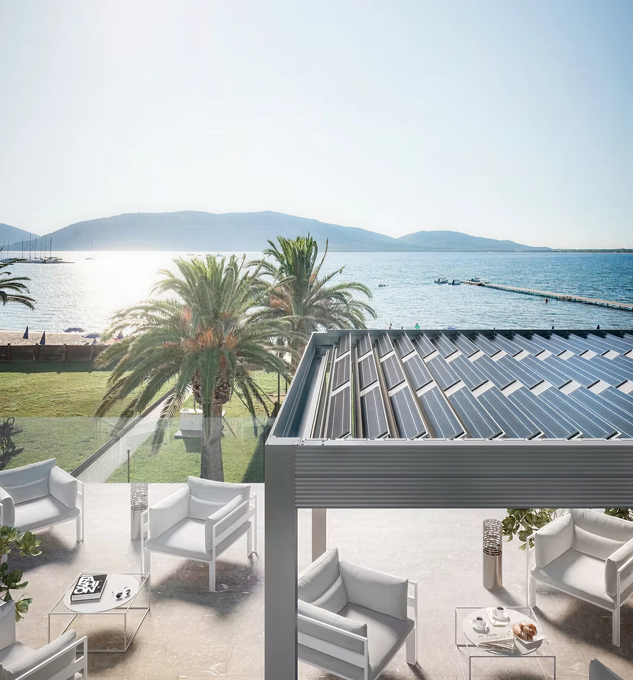 Moderne Terrasse mit weißem Loungemöbel und Blick auf Meer und Palmen.