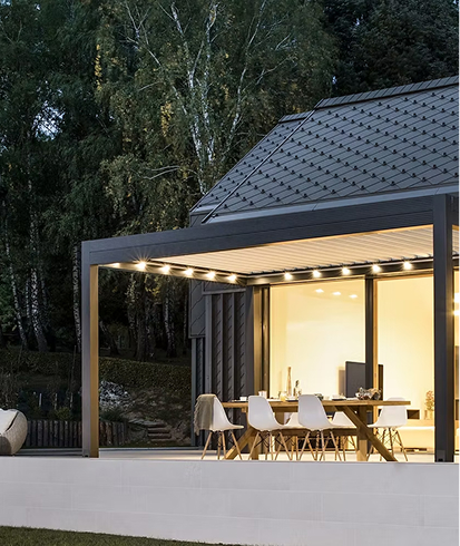 Moderne Terrasse mit Essbereich und Beleuchtung neben einem Haus in der Dämmerung.