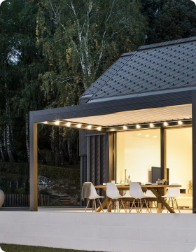 Moderne Terrasse mit Essbereich und Beleuchtung bei Abenddämmerung.