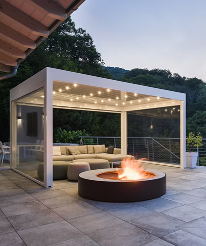 Moderne Terrasse mit Überdachung, Feuerschale und gemütlicher Sitzgruppe bei Abenddämmerung.