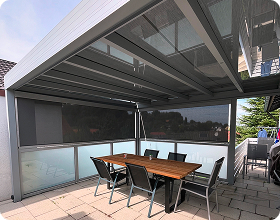 Überdachte Terrasse mit Tisch und Stühlen, umgeben von Sichtschutzwänden.