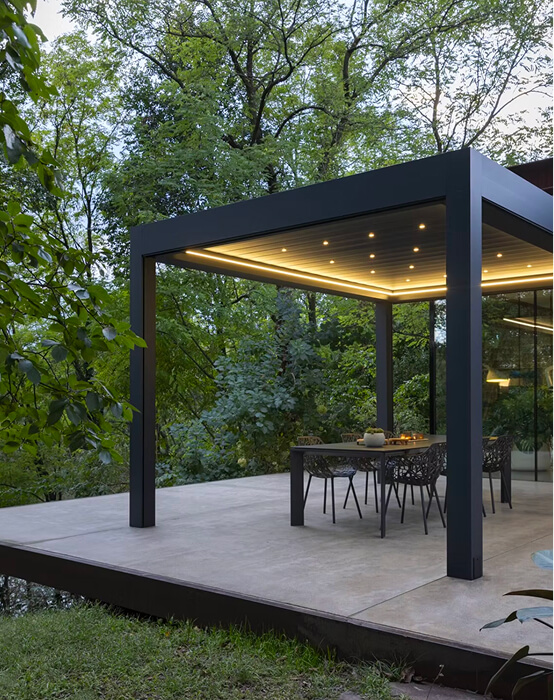 Moderne Pergola mit Tisch und Stühlen auf Terrasse im Grünen