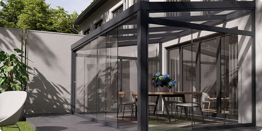 Moderner Wintergarten mit Glaswänden und Möbeln im Außenbereich.