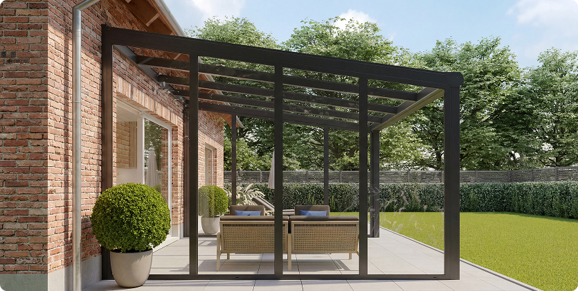Glasüberdachte Terrasse mit Ziegelwand, Möbel und grüner Garten im Hintergrund.