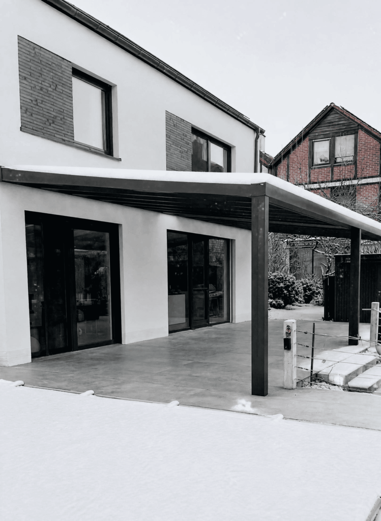 Modernes Haus mit Terrassen&uuml;berdachung im Schnee.