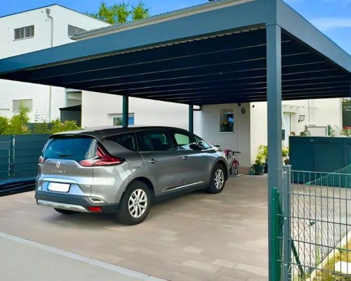 Ein Auto parkt unter einem modernen Carport neben einem Wohnhaus.