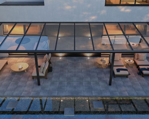Moderne Terrasse mit Glasüberdachung, eleganter Einrichtung und Beleuchtung bei Abenddämmerung.