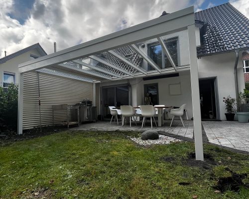 Überdachte Terrasse mit Gartenmöbeln und integrierter Grillstation im modernen Hausgarten.