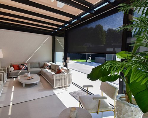 Moderner Wintergarten mit bequemen Möbeln unter Glasdach und Sonnenschutz.